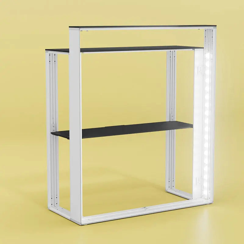 Rahmenstruktur des Counter MAX Messetheke ohne Stoffbanner– Aluminiumprofil mit zwei schwarzen Ablageböden und integrierter LED-Beleuchtung auf gelbem Hintergrund.
