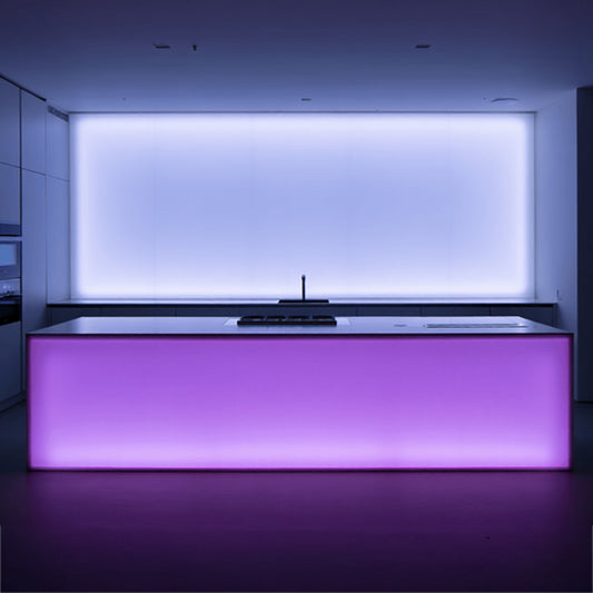 Küche mit einer Kücheninsel; an der Vorderseite der Insel eine LED-Wand mit Kanteneinstrahlung in Rosa, dahinter eine LED-Wand in Weiß mit Kanteneinstrahlung.