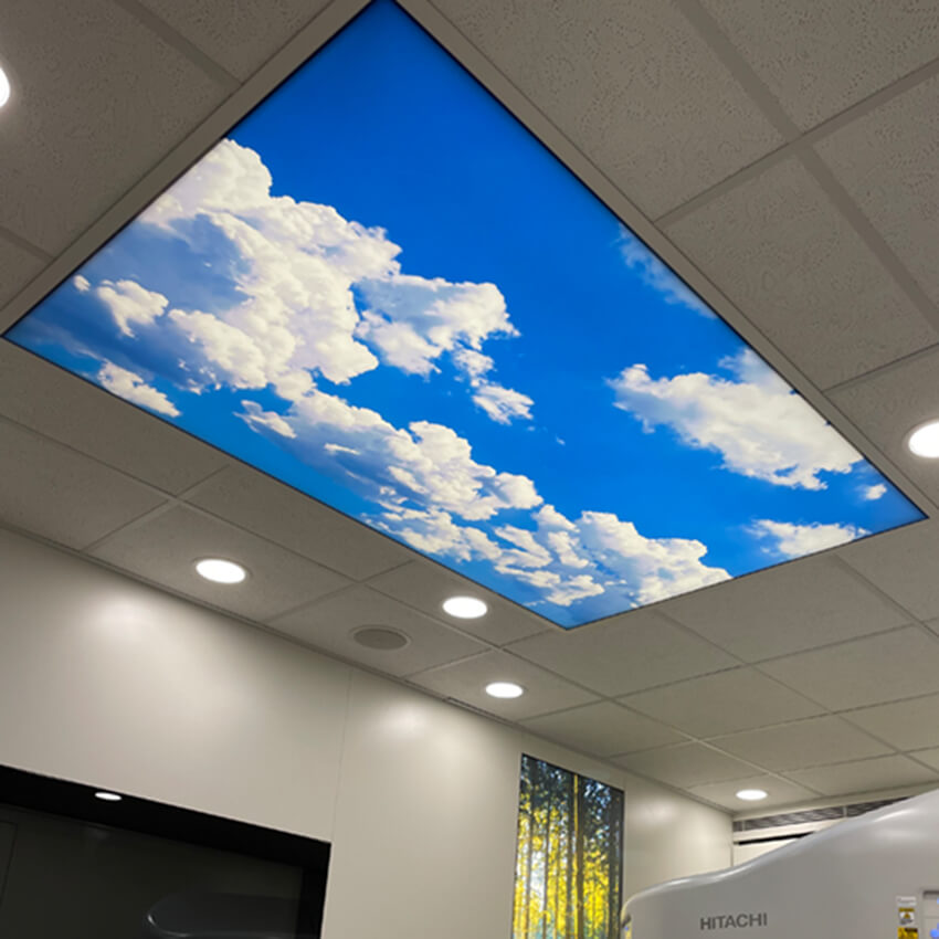 LED-Lichtdecke mit Himmelmotiv und weißen Wolken, integriert in eine Rasterdecke.