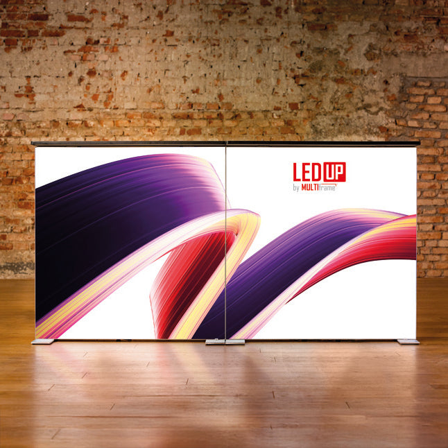 Zwei verbundene LEDUP Counter Systeme mit farbigem Textildruckmotiv stehen nebeneinander vor einer Backsteinwand auf Holzboden.