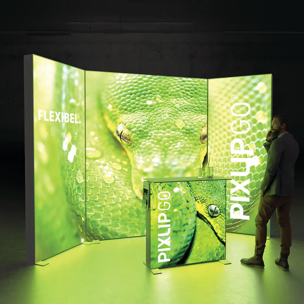 Beleuchteter PIXLIP GO Messestand mit modularem Rahmensystem und Stoffbanner in auffälligem Grün, bestehend aus mehreren verbundenen Messewänden und passender Theke.