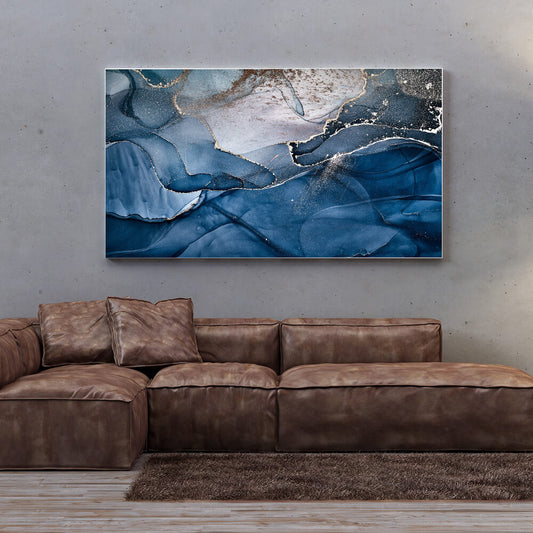 Rechteckiges blaues Akustikbild in Marmoroptik mit goldenen Akzenten über einem braunen Ledersofa