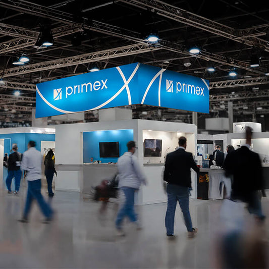 Leuchtender LED-Deckenhänger in U-Form mit blauem Branding hängt über einer Messehalle mit modernem Stahlträger-Dach und Besuchern darunter.