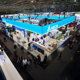 Großformatiger LED-Deckenhänger über einem Messestand mit umlaufender Markenpräsenz. Zentrale Blickfanglösung für maximale Sichtbarkeit und Orientierung in stark frequentierten Messehallen.
