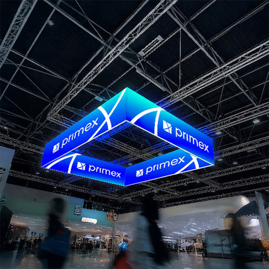 Quadratischer LED-Deckenhänger mit blauem Primex-Logo, der an einer Metallträger-Konstruktion in einer Messehalle befestigt ist.