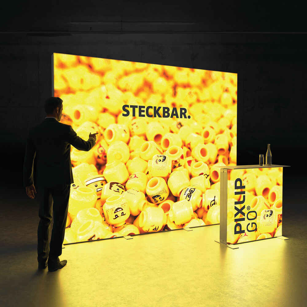Beleuchteter PIXLIP GO Messestand mit modularer Rückwand und passender Theke in leuchtendem Gelb.