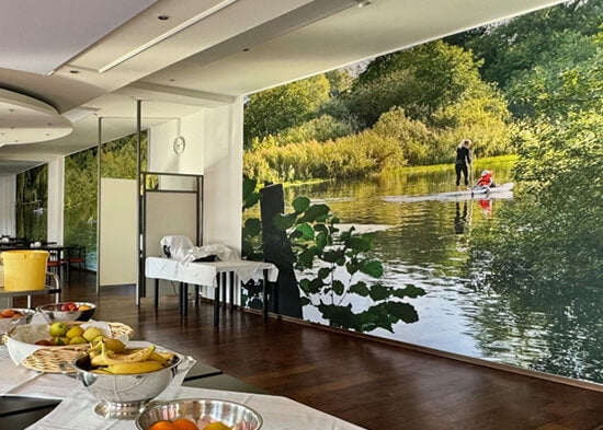 Akustikbild mit einem See-Motiv, auf dem eine Frau Stand-up-Paddling betreibt, im Speisesaal eines Klinikums.