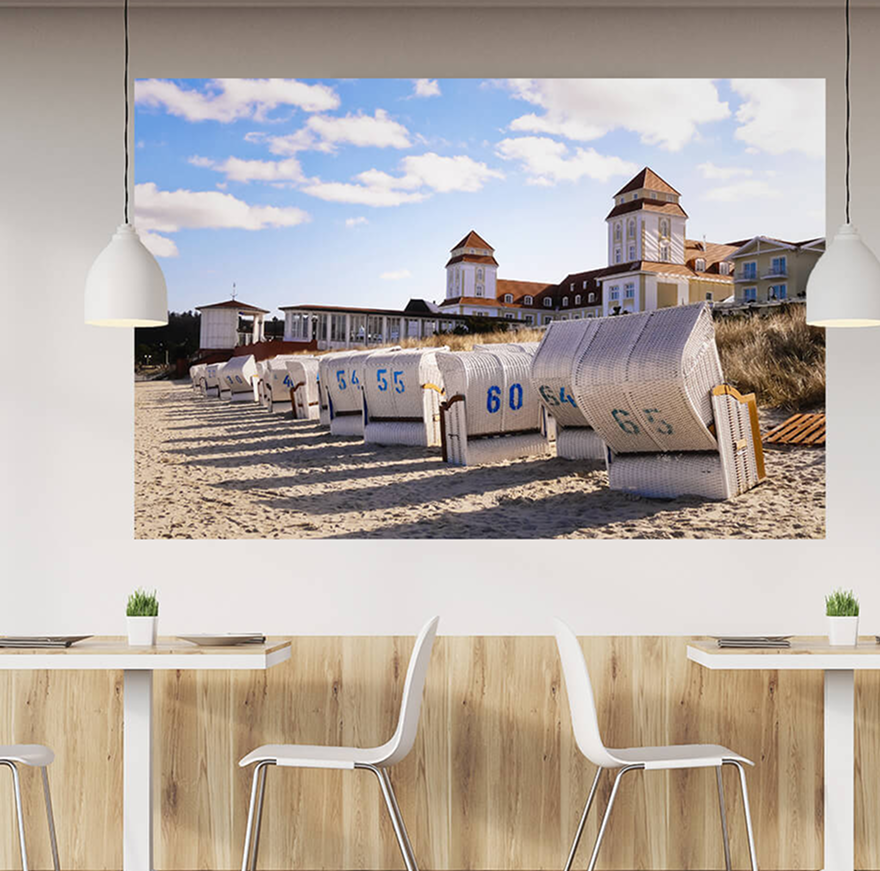 Gastro-Bereich mit Akustikbild an der Wand: ein Strandmotiv mit Strandkörben nebeneinander.