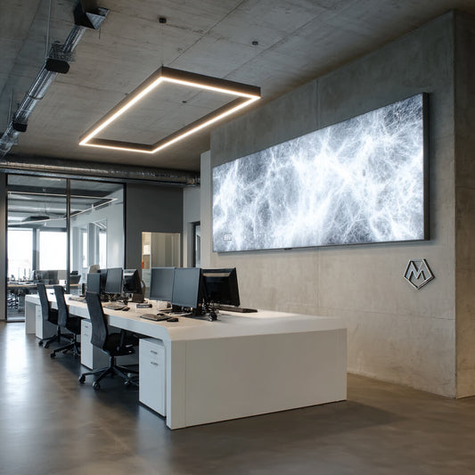Modernes Büro mit weißen Schreibtischen, schwarzen Stühlen, Computern und einem großen LED-Spannrahmen als Flächenlicht mit fadenartigem, abstraktem Muster.