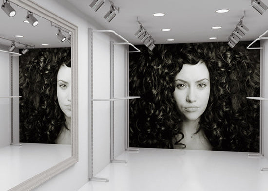 In einem Retail-Bereich hängt ein Akustikbild, das als Motiv eine Frau mit auffälligen, voluminösen Locken zeigt und dadurch einen modernen, stilvollen Akzent setzt.