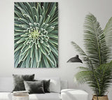 Modernes Wohnzimmer mit großformatigem Akustikbild einer grünen Blüten- oder Pflanzenstruktur über einem weißen Sofa, daneben eine hohe Zimmerpflanze.