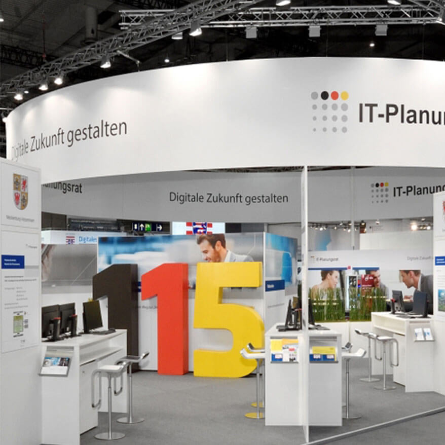 Messestand mit großflächigem runden Deckenhänger und integrierten Präsentationsflächen für klare Markenkommunikation. Strukturierte Standgestaltung für Messen, Events und Promotionbereiche