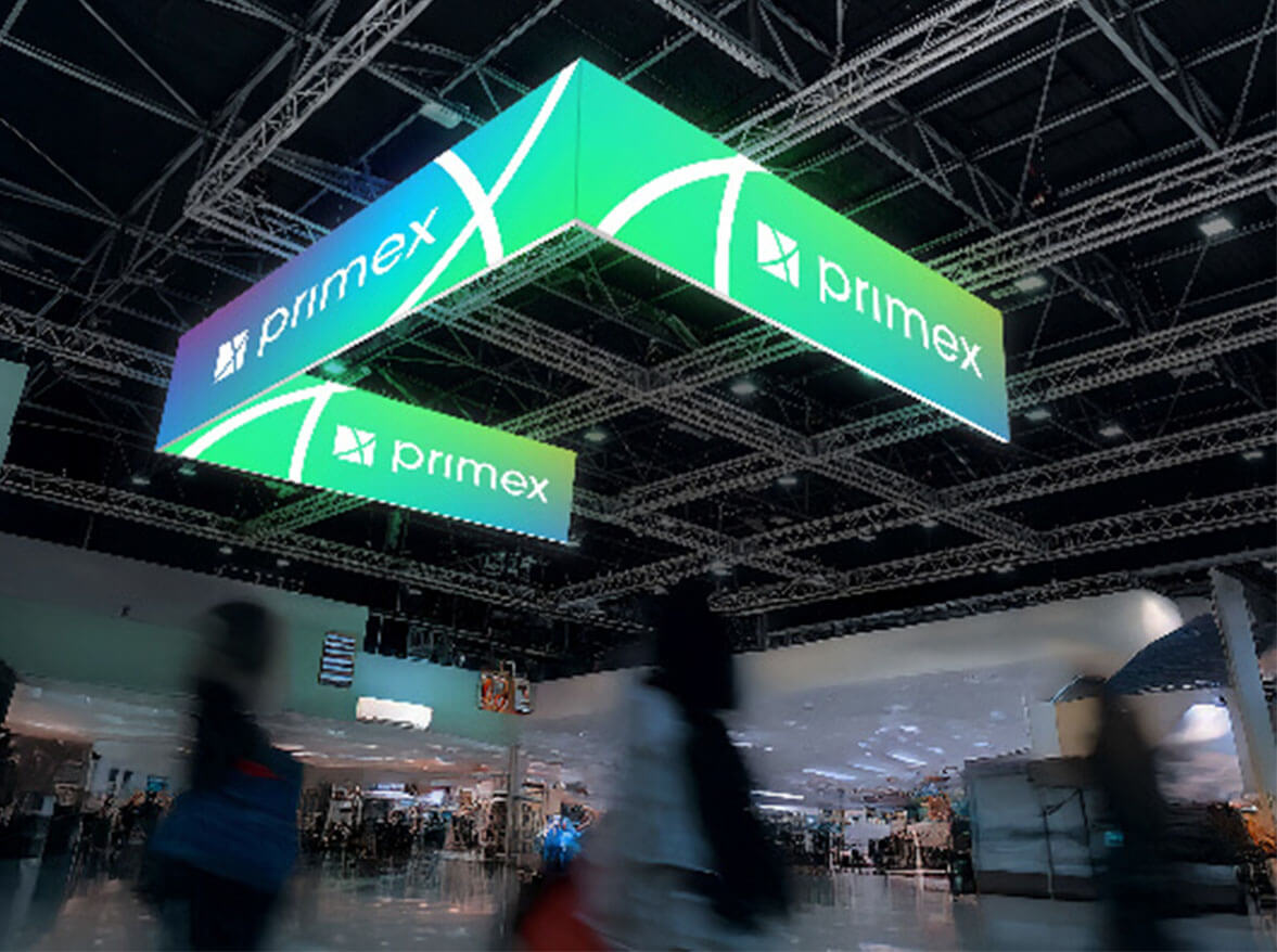 U-förmiger LED-Messedeckenhänger mit Primex-Logo über einem Messestand.