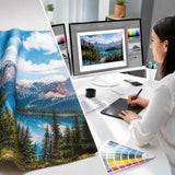 Grafikdesignerin beim Premium-Datencheck am Monitor neben einem unkonfektionierten Textil-Andruck mit Landschaftsmotiv.
