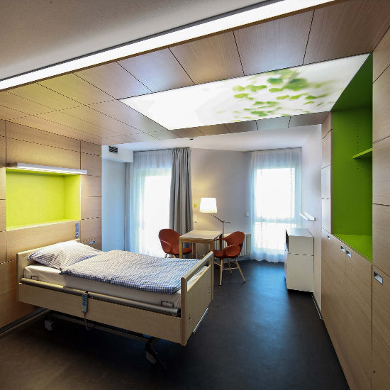 Patientenzimmer mit einer beruhigenden LED-Lichtdecke mit Naturmotiv, die für eine freundliche und entspannende Atmosphäre sorgt.