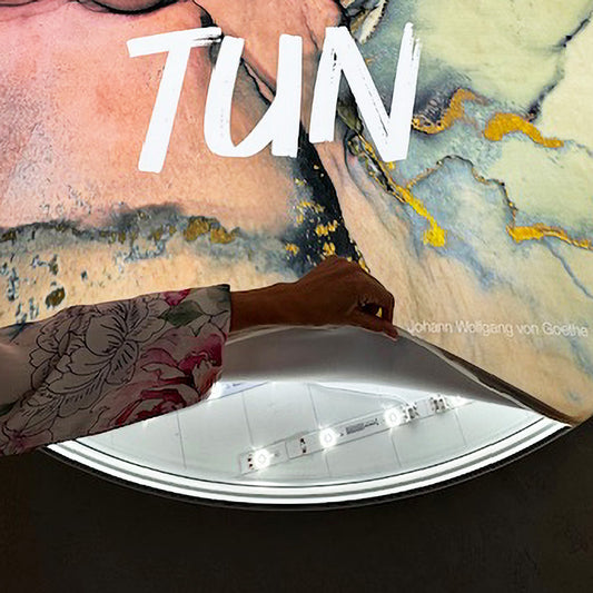 Nahaufnahme von einem Runden LED-Rahmen, bei dem die Textildruck an der Kante gelöst wird und die dahinterliegende LED-Beleuchtung sichtbar ist.