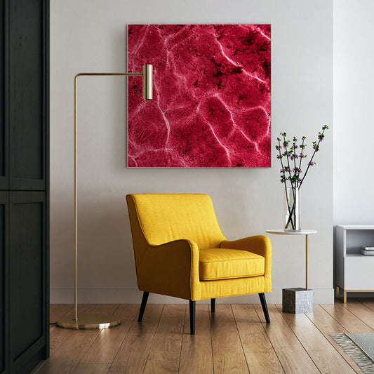 Quadratisches Akustikbild einer magentafarbenen Reflektion im Wasser, hinter einem gelben Sessel